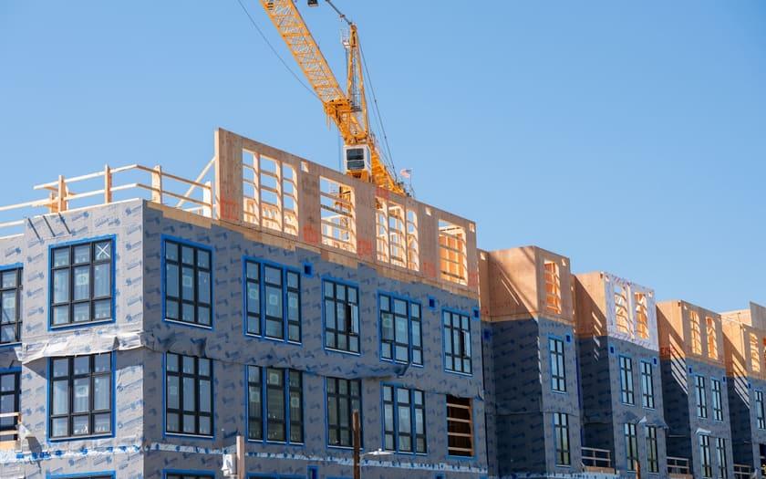 Building facade under construction with insulation wrap and crane